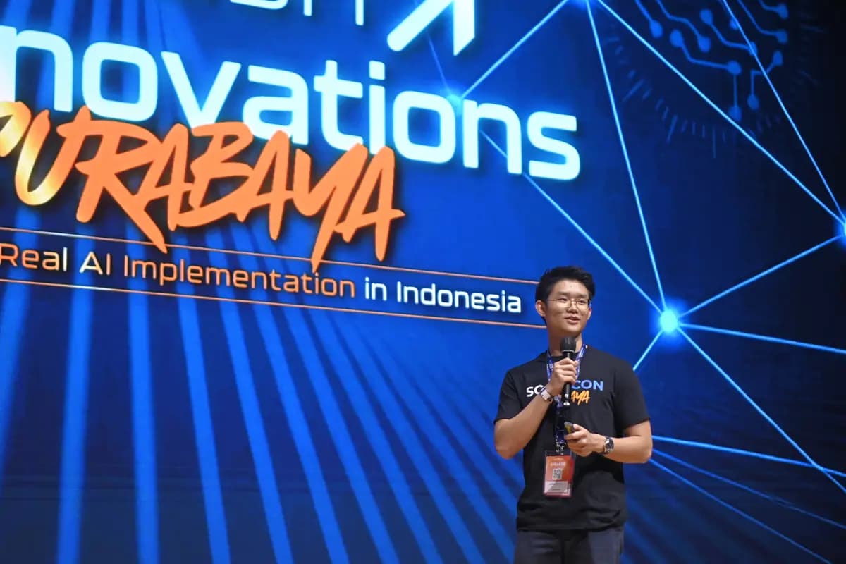 A speaker in front of the Real AI Implementation backdrop at SCALECON Surabaya 2026